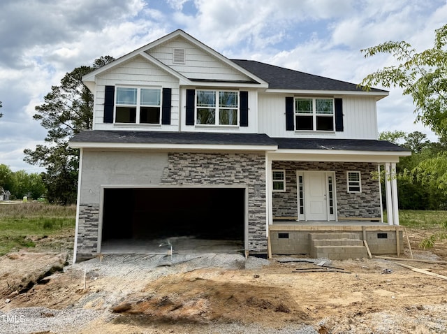 view of front of home with a porch, driveway, stone siding, and an attached garage