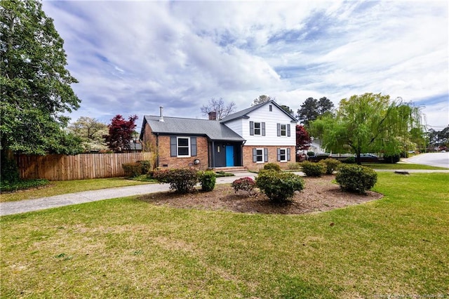 tri-level home featuring a chimney, a front yard, fence, and brick siding