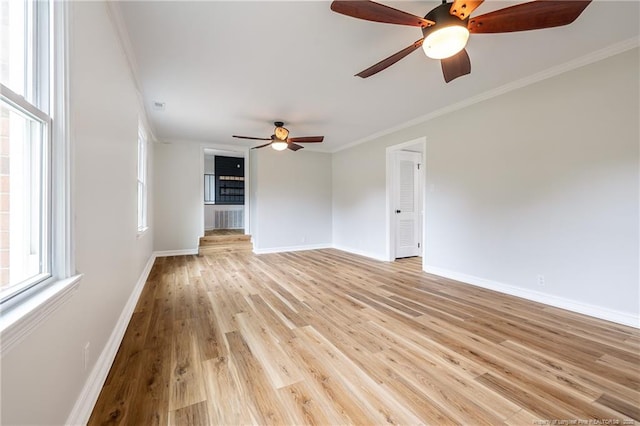 empty room featuring light wood-type flooring, crown molding, baseboards, and ceiling fan