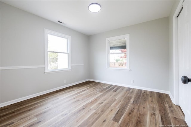 spare room with baseboards, visible vents, and wood finished floors