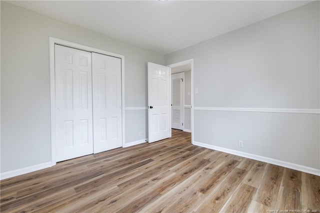 unfurnished bedroom with a closet, baseboards, and wood finished floors