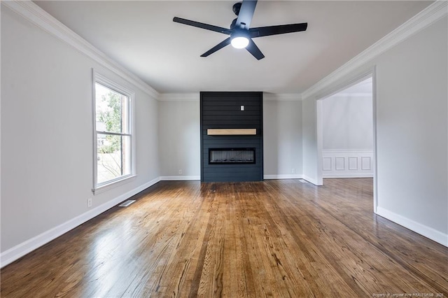 unfurnished living room featuring a large fireplace, wood finished floors, and ornamental molding