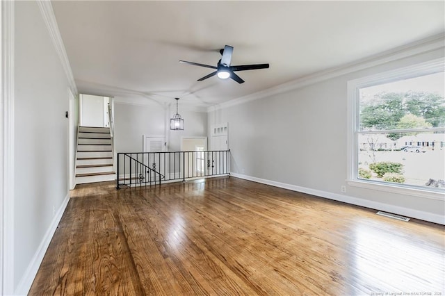 spare room with visible vents, crown molding, wood finished floors, and ceiling fan