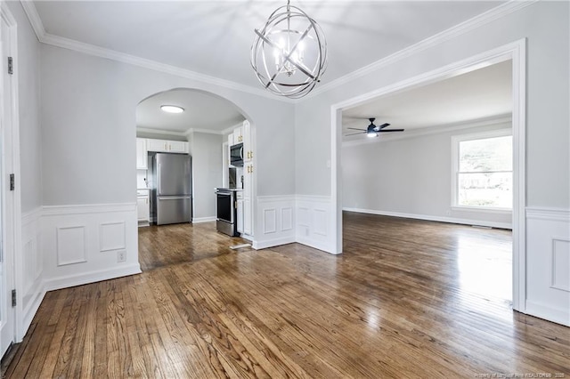 unfurnished dining area featuring ceiling fan with notable chandelier, arched walkways, ornamental molding, and dark wood-type flooring