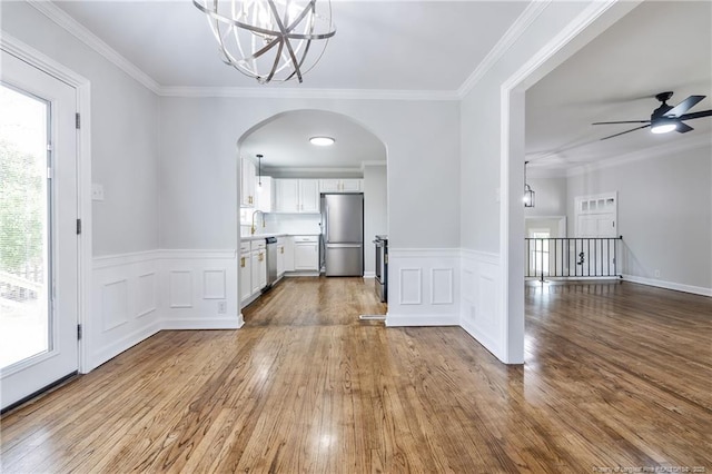 unfurnished dining area with arched walkways, crown molding, and dark wood-type flooring