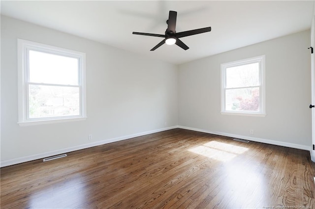 empty room with baseboards, visible vents, wood finished floors, and a ceiling fan