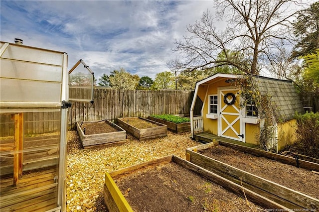 view of yard featuring an outbuilding, fence, a storage unit, and a vegetable garden