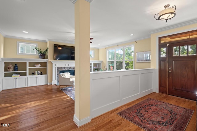 997 Windy Rd, Apex, NC 27502 - foyer with crown molding, a stone fireplace, wood finished floors, wainscoting, and recessed lighting