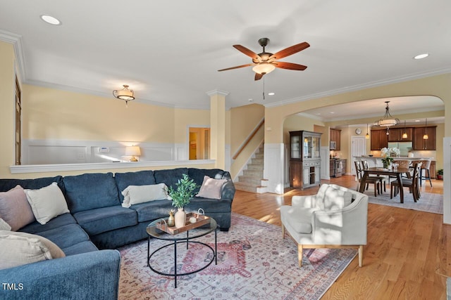 997 Windy Rd, Apex, NC 27502 - living room featuring arched walkways, light wood-type flooring, ceiling fan, ornamental molding, and stairway