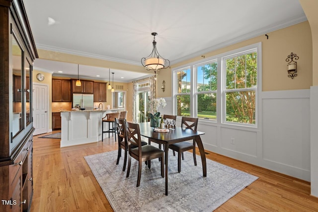 997 Windy Rd, Apex, NC 27502 - dining room with crown molding, light wood-style floors, a wainscoted wall, and a decorative wall