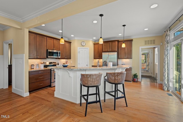 997 Windy Rd, Apex, NC 27502 - kitchen featuring appliances with stainless steel finishes, a breakfast bar, light wood finished floors, recessed lighting, and crown molding