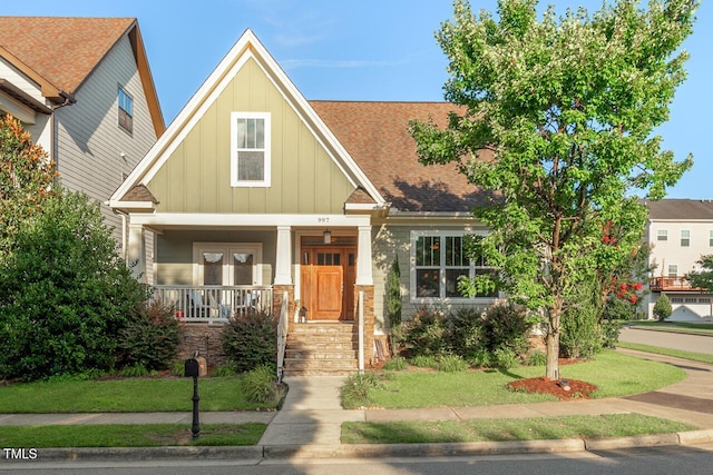 997 Windy Rd, Apex, NC 27502 - craftsman-style home with board and batten siding, covered porch, a shingled roof, and a front lawn
