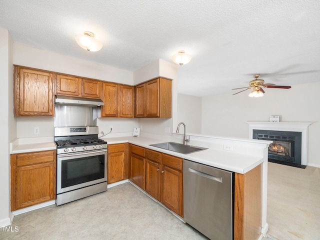 5504 Cumberland Plain Dr, Raleigh, NC 27616 - kitchen featuring brown cabinets, under cabinet range hood, a sink, a peninsula, and appliances with stainless steel finishes
