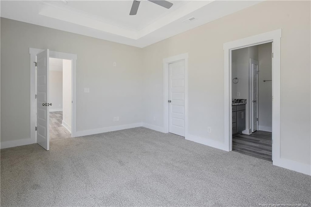 4915 High Branch Ct, Stedman, NC 28391 - unfurnished bedroom featuring carpet flooring, a tray ceiling, connected bathroom, and a ceiling fan