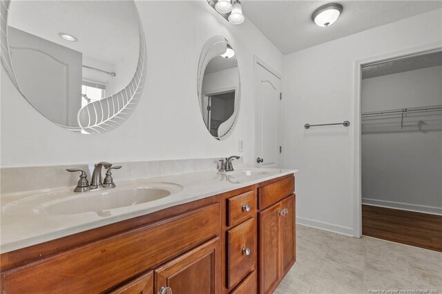 193 Wind Brook Ct, Raeford, NC 28376 - bathroom featuring baseboards, double vanity, a sink, and a spacious closet