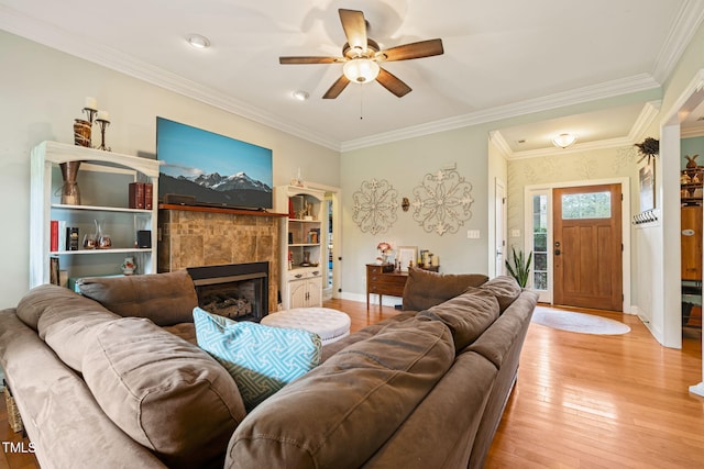 8437 Little Woody Ct, Zebulon, NC 27597 - living room with a tiled fireplace, a ceiling fan, light wood-type flooring, baseboards, and ornamental molding