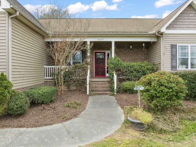 8437 Little Woody Ct, Zebulon, NC 27597 - entrance to property featuring covered porch, a shingled roof, and brick siding