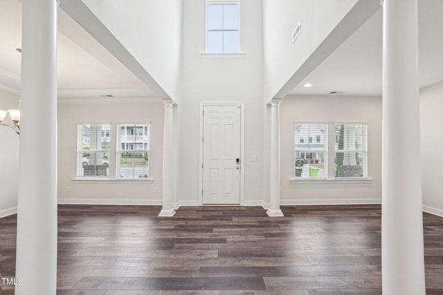 foyer entrance featuring dark wood-style flooring, a healthy amount of sunlight, and decorative columns