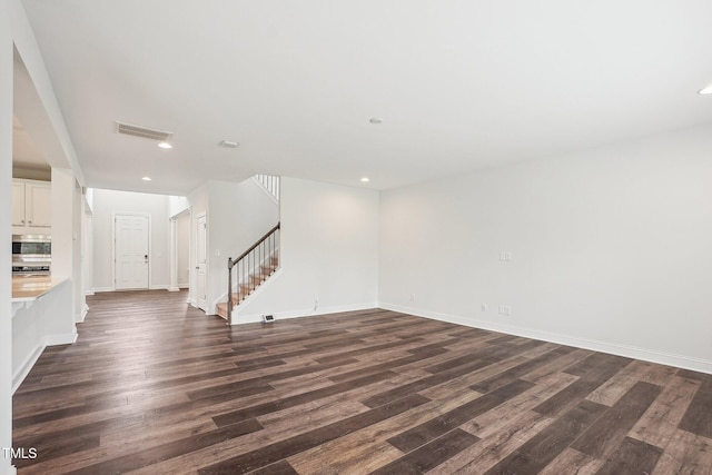 unfurnished living room with visible vents, baseboards, recessed lighting, stairway, and dark wood finished floors