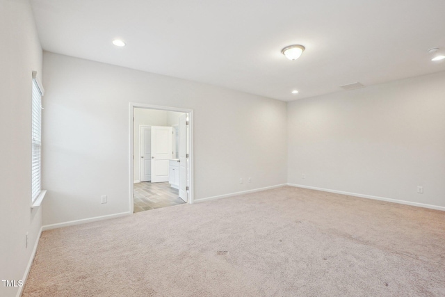 spare room featuring light carpet, baseboards, and recessed lighting