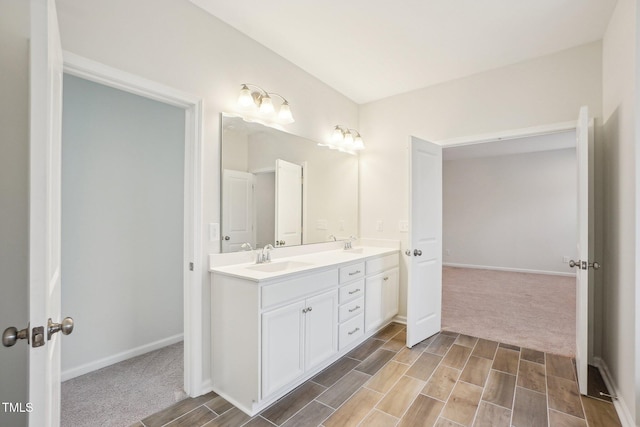 bathroom featuring baseboards, double vanity, a sink, and wood finish floors