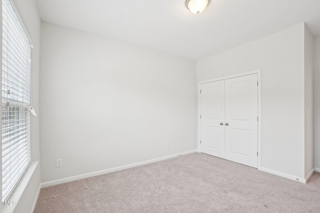 unfurnished bedroom featuring multiple windows, a closet, and carpet