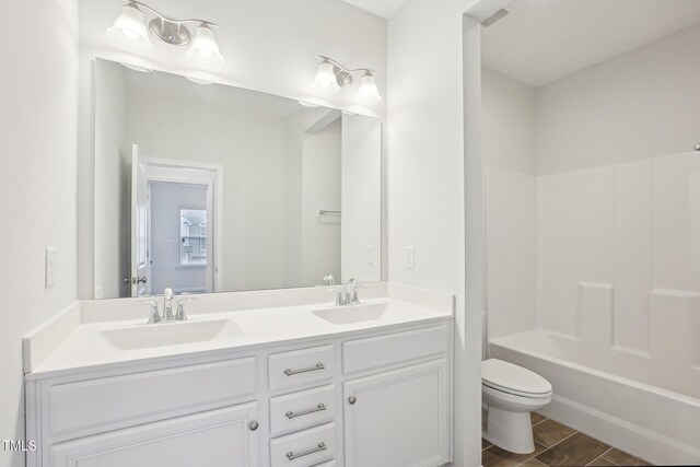 bathroom with double vanity, tub / shower combination, toilet, and a sink