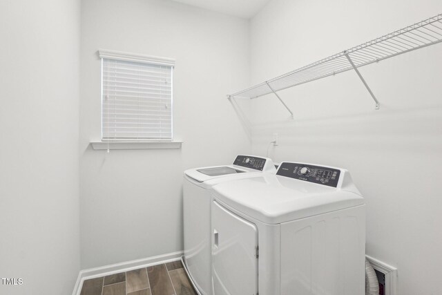 laundry room with wood tiled floor, washing machine and dryer, laundry area, and baseboards