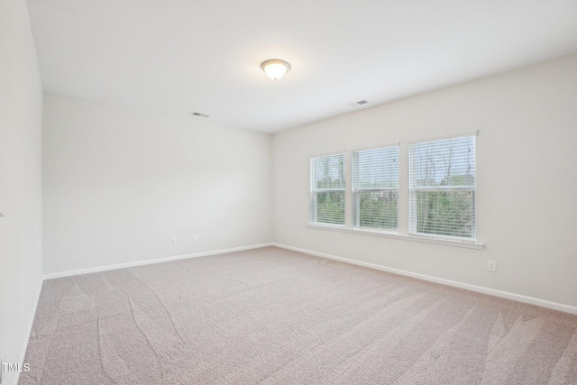 empty room with baseboards, carpet flooring, and visible vents
