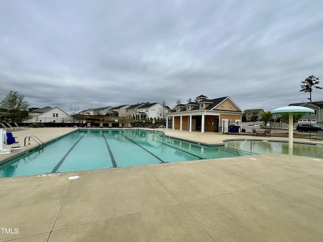 community pool with fence and a patio area