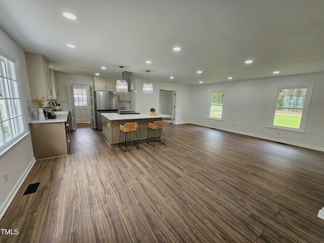 kitchen with light countertops, freestanding refrigerator, dark wood-type flooring, visible vents, and wall chimney exhaust hood