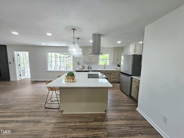 kitchen with dark wood-style flooring, light countertops, freestanding refrigerator, a kitchen island, and island range hood