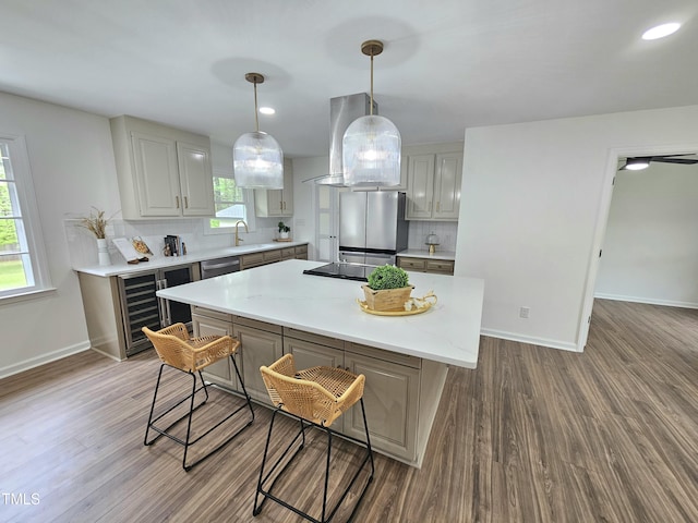 kitchen featuring tasteful backsplash, wall chimney range hood, a kitchen island, light countertops, and stainless steel appliances