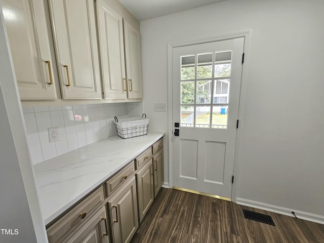 doorway with visible vents, baseboards, and dark wood-style floors
