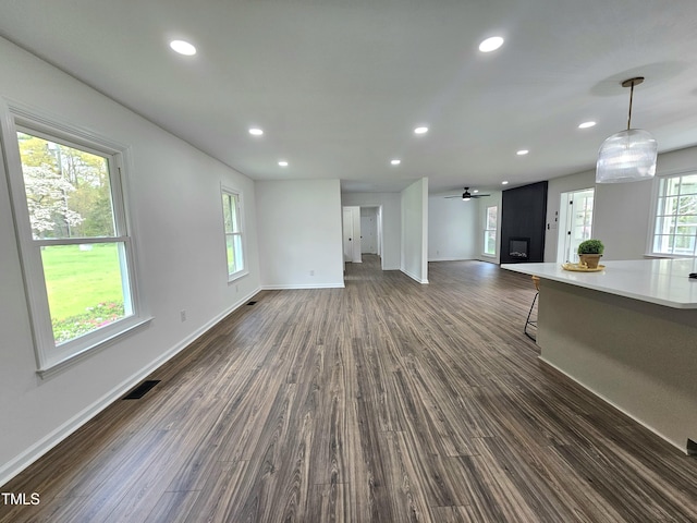 unfurnished living room featuring baseboards, dark wood finished floors, visible vents, and recessed lighting