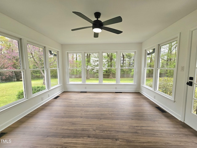 unfurnished sunroom featuring wood finished floors, baseboards, visible vents, and a wealth of natural light