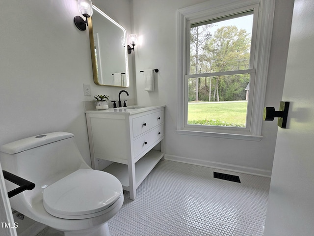 bathroom with toilet, vanity, baseboards, and visible vents