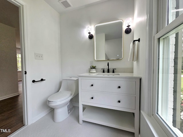 bathroom featuring visible vents, toilet, vanity, and baseboards