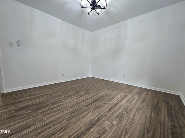 unfurnished room with baseboards, an inviting chandelier, and dark wood finished floors