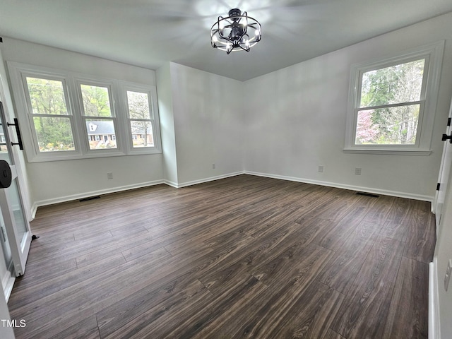 spare room featuring visible vents, baseboards, a notable chandelier, and dark wood-style floors