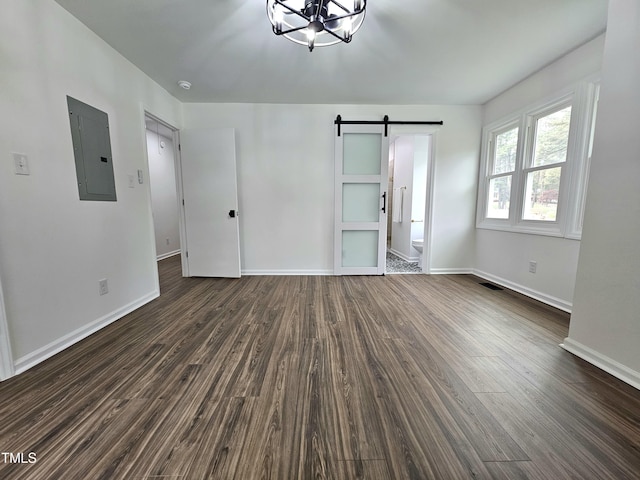 interior space featuring baseboards, a barn door, electric panel, a chandelier, and dark wood-type flooring
