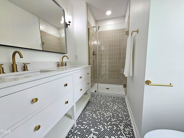 bathroom featuring double vanity, baseboards, a sink, and a stall shower