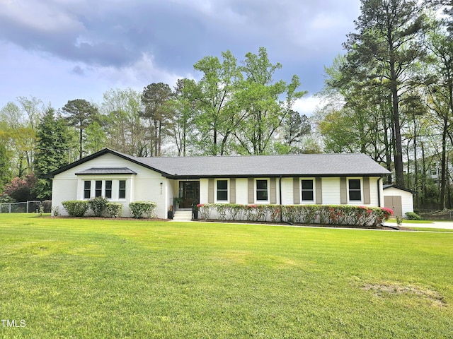 single story home featuring a front yard, fence, a shed, and an outbuilding