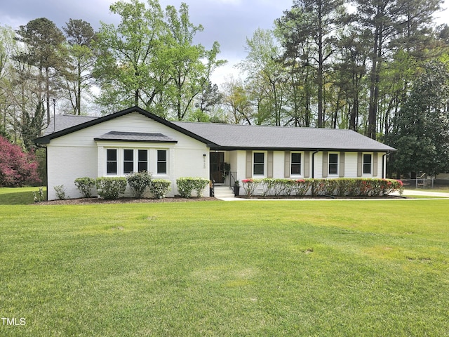 ranch-style home featuring roof with shingles and a front lawn