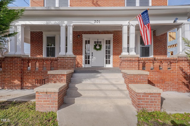 property entrance featuring brick siding and a porch
