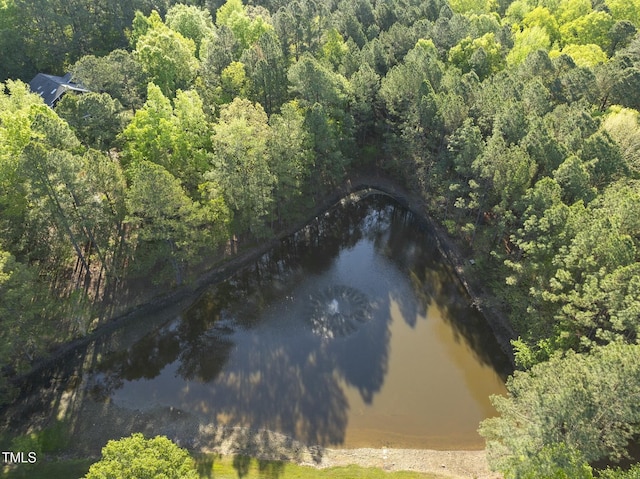 aerial view of property and surrounding area with a forest and a nearby body of water