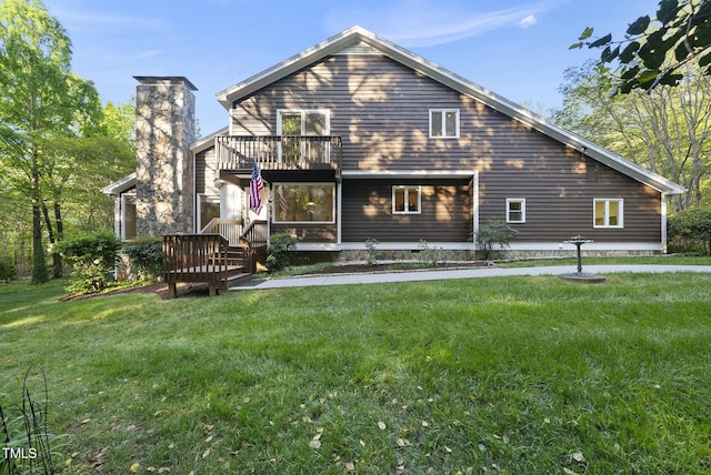 back of house with a balcony and a yard