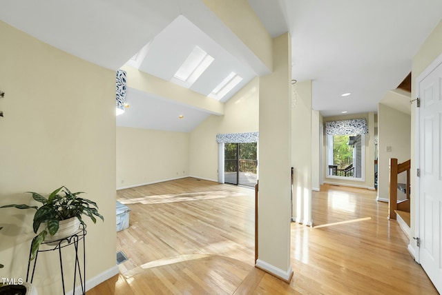 bonus room featuring light wood-type flooring, beam ceiling, baseboards, high vaulted ceiling, and a skylight