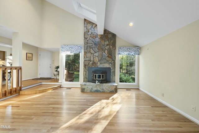 unfurnished living room featuring wood finished floors, high vaulted ceiling, and baseboards