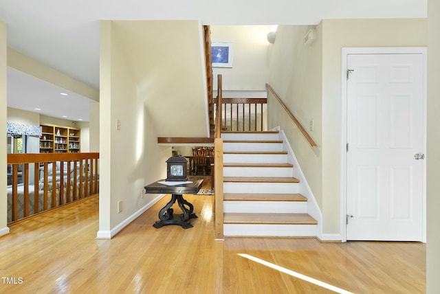 stairs with wood finished floors, baseboards, and recessed lighting